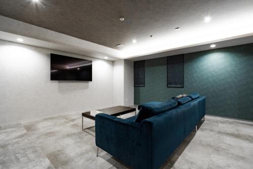 a living room with a blue couch and a tv at Randor Hotel Hiroshima Prestige in Hiroshima