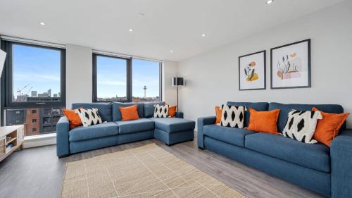 a living room with two blue couches and orange pillows at Host & Stay - The Baltic Penthouse 2 in Liverpool