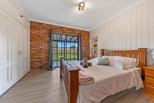 um quarto com uma cama e uma parede de tijolos em The Weltara - 6 bedrooms House Near Anna Bay em Williamtown