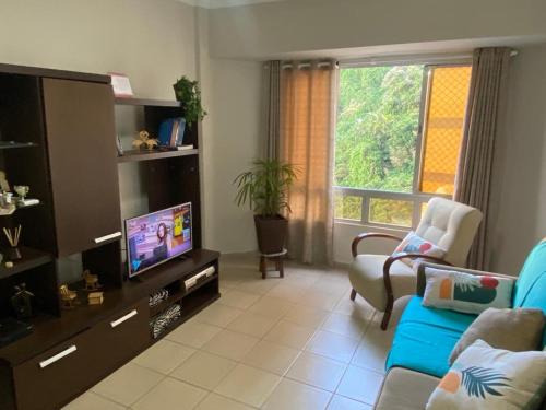 uma sala de estar com uma televisão de ecrã plano e um sofá em Apartamento Guarujá Pitangueiras 50 metros Praia/3 Dormitórios/Vista do Mar, Sol da manhã no Guarujá