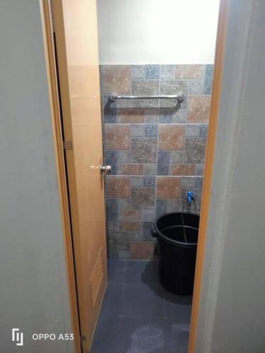 a bathroom with a toilet and a tiled wall at TerisitaPlace - DriveBy RestStop in Taytay