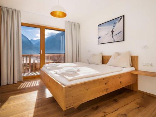 een slaapkamer met een bed en een balkon met uitzicht op de bergen bij Exclusive chalet with sauna and unique view of the glacier in Neukirchen am Großvenediger