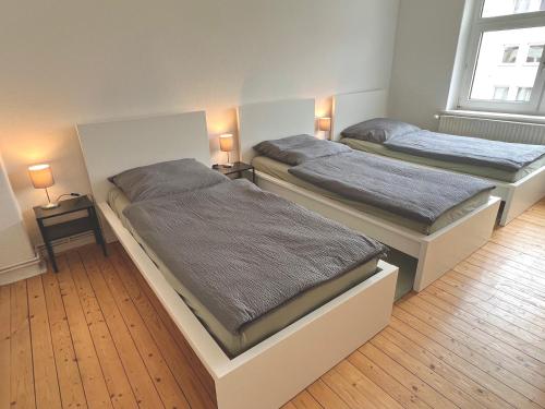 two beds in a room with two lamps on tables at 3 Betten Unterkunft Vahrenwald-List in Hannover
