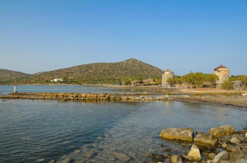 a body of water with rocks and mountains in the background at Elounda Island Villas in Elounda
