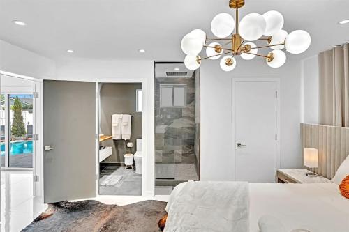 a bedroom with a white bed and a chandelier at Luxury Hollywood Home, Heated Pool, Casino Nearby in Hollywood
