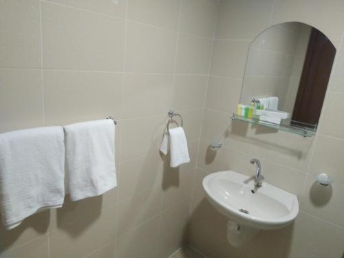 Baño blanco con lavabo y espejo en Rayan Hotel Suites, en Amán
