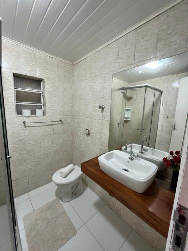 W łazience znajduje się umywalka, toaleta i lustro. w obiekcie Chalé Modesto w mieście Campos do Jordão