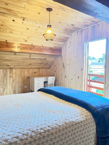sypialnia z dużym łóżkiem w drewnianym pokoju w obiekcie Chalé Modesto w mieście Campos do Jordão