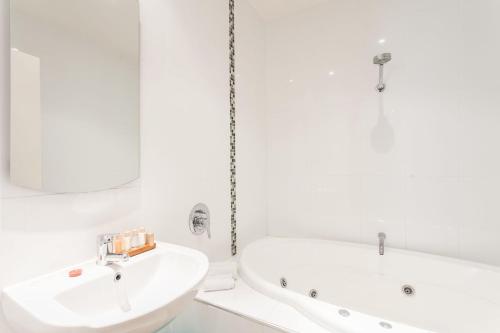 a white bathroom with a sink and a tub at Anglesea River Apartment 23 in Anglesea