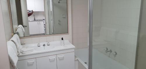 a white bathroom with a shower and a sink at Beautiful, inner city, renovated top floor 2-bedroom apartment in Canberra