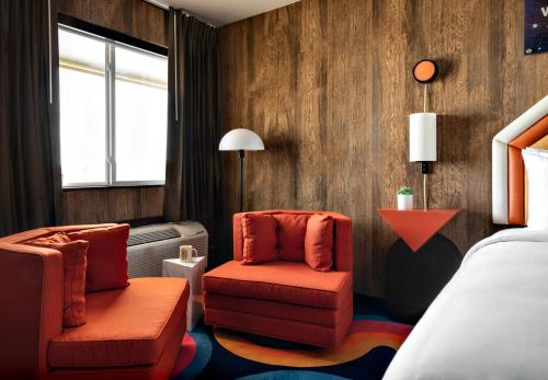 Habitación de hotel con 2 sillas y 1 cama en Americana Motor Hotel en Flagstaff