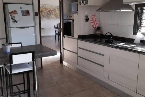 a kitchen with white cabinets and a table and a refrigerator at Casa con piscina en Maipú, Mendoza in Maipú