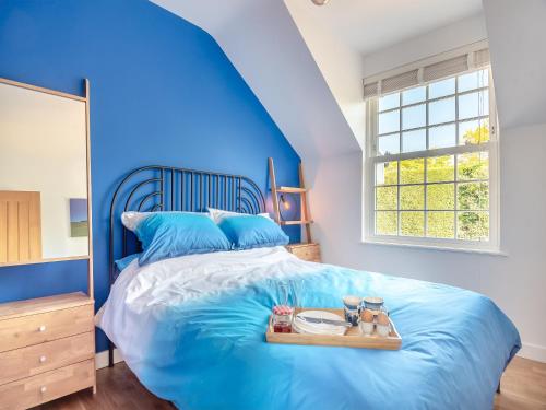 a blue bedroom with a bed with a tray on it at Gunns Loft in Smallburgh