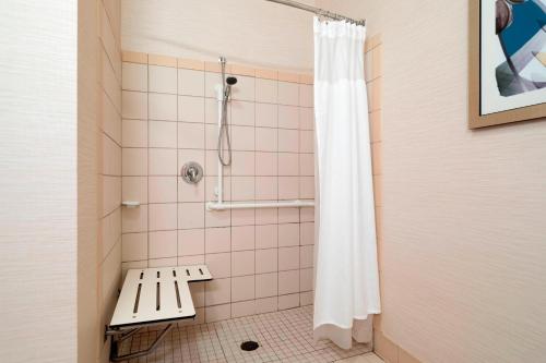 une douche avec un banc et un rideau de douche dans l'établissement Fairfield Inn & Suites by Marriott State College, à State College