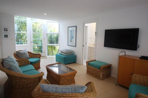 a living room with wicker chairs and a flat screen tv at Eureka in Boomerang Beach