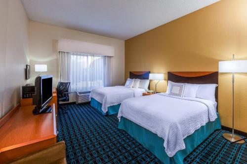 a hotel room with two beds and a flat screen tv at Fairfield Inn & Suites by Marriott Rogers in Rogers