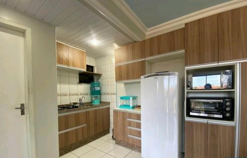 uma cozinha com um frigorífico branco e armários de madeira em Crystal Park Flat em Aquiraz