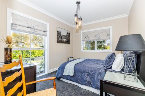 a bedroom with a bed and a desk and two windows at Sweet Magnolia 1 or 2 BR Suite St Kilda Cambridge with Complimentary Continental Breakfast in Cambridge