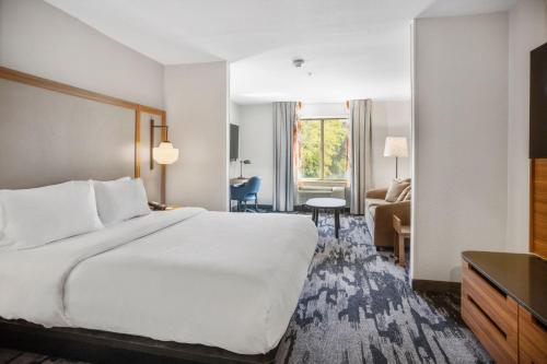 ランチョ・コルドバにあるFairfield Inn & Suites Rancho Cordovaの大きなベッドとリビングルームが備わるホテルルームです。