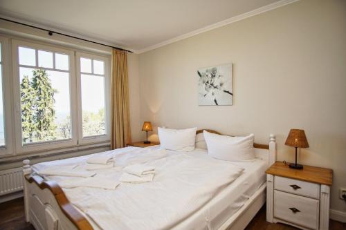 1 cama blanca en un dormitorio con ventana en Ferienwohnung mit traumhaftem Meerblick - Haus am Meer FeWo 07, en Lohme