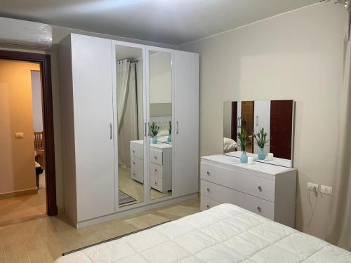a bedroom with white furniture and a large mirror at ازها العين السخنه in Ain Sokhna