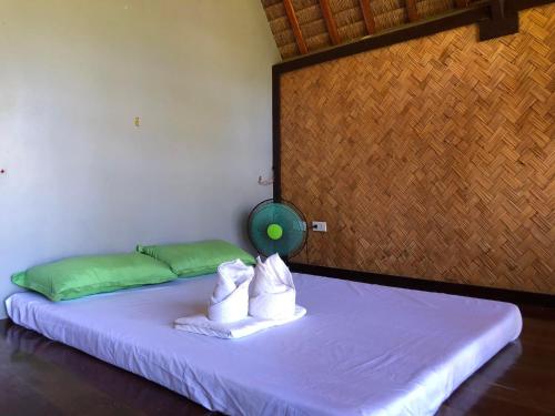 Una cama con dos toallas y una bola verde. en Tanawin en El Nido