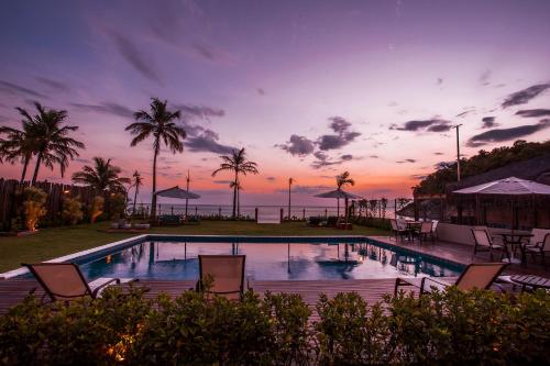 a swimming pool with chairs and palm trees at sunset at Residencial Marina Del Sol in Pauba