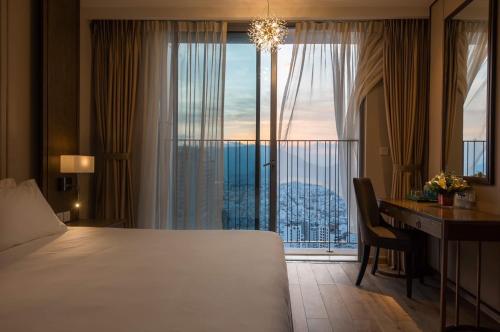 a hotel room with a bed and a desk and a window at Panorama Apartment Nha Trang in Nha Trang