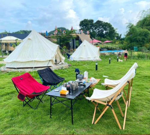 a table and two chairs and tents in a field at Caofong Glamping Village in Hòa Bình
