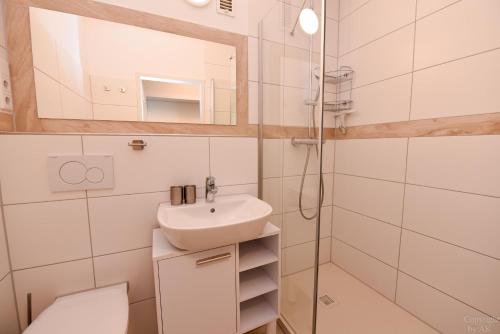 a bathroom with a sink and a toilet and a mirror at Haus "Atlantic" Appartement ATL 604B in Cuxhaven