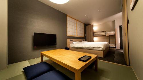 ein Hotelzimmer mit einem Bett, einem Tisch, einem Bett und einem TV in der Unterkunft ALPHABED INN Fukuoka Ohori Park in Fukuoka