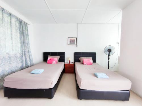 2 Betten in einem Zimmer mit rosa und blauen Kissen in der Unterkunft D' Limbai Cottage in Ranau