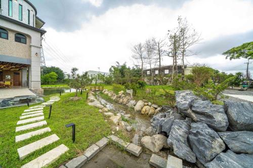 a rock retaining wall next to a building with a creek at 森堡休閒莊園 in Yilan City
