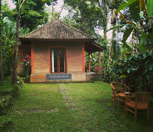 a small building with a table and chairs in a yard at Purana Guest House in Tabanan