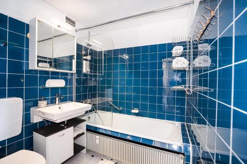 La salle de bains est pourvue de carrelage bleu, d'une baignoire et d'un lavabo. dans l'établissement Fewo Poseidon, Ostsee-Familienurlaub am Hansapark mit Schwimmbad, à Sierksdorf