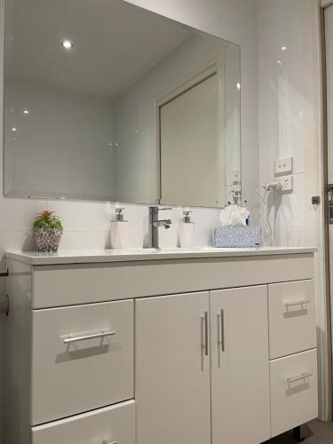 a white bathroom with a sink and a mirror at Cooma Hotel in Cooma