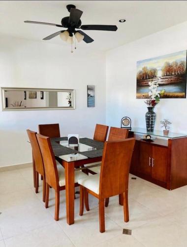 a dining room with a table and chairs and a ceiling fan at Homecancun in Cancún