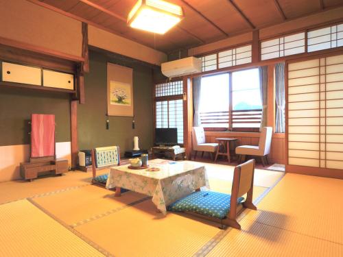 sala de estar con mesa y sillas en una habitación en Ougiya Ryokan, en Toyooka