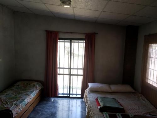 a bedroom with two beds and a large window at Don Castro Alojamiento Serrano in San Roque