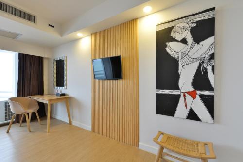 a living room with a tv on a wall at D Varee Jomtien Beach, Pattaya in Jomtien Beach