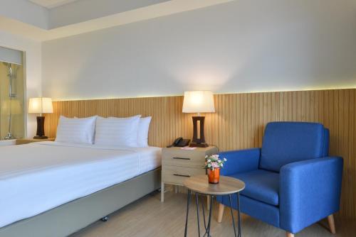a hotel room with a bed and a blue chair at D Varee Jomtien Beach, Pattaya in Jomtien Beach