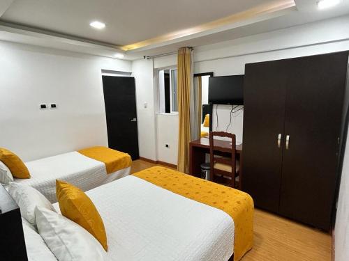 Habitación de hotel con 2 camas y escritorio en Hotel Lagos Latin America, en Pasto