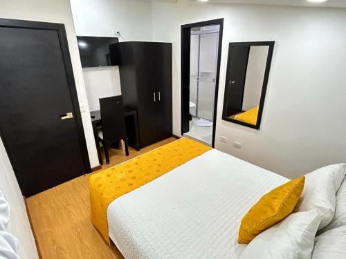 a bedroom with a white bed and a yellow pillow at Hotel Lagos Latin America in Pasto
