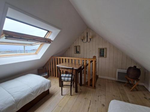 ein Schlafzimmer mit einem Bett und einem Tisch im Dachgeschoss in der Unterkunft Set of 2 houses in Plougasnou, 300 m from the coast in Plougasnou