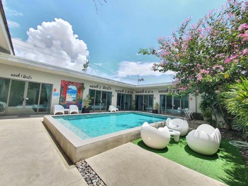ein Pool mit zwei weißen Stühlen und ein Haus in der Unterkunft Areeca Private pool villas in Thalang