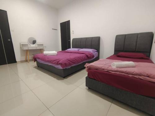 two beds sitting in a room with at Sakura homestay 5 bedrooms - Spring Lopeng 14 pax in Miri