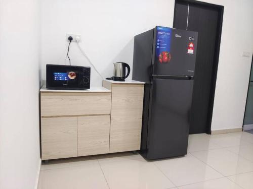 a black refrigerator next to a counter with a microwave at Sakura homestay 5 bedrooms - Spring Lopeng 14 pax in Miri