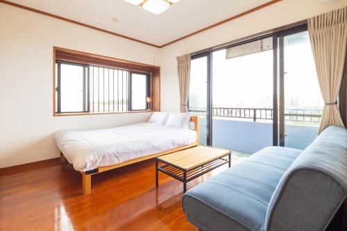 um quarto com uma cama, um sofá e janelas em Oriental Villa - Vacation STAY 09167v em Ishigaki