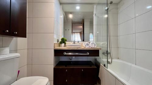 a bathroom with a sink and a toilet and a mirror at Apartamentos City Centro Los Leones in Santiago