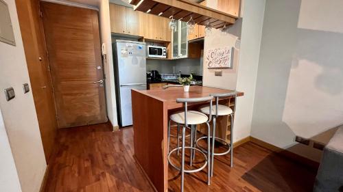 a kitchen with a counter with stools in it at Apartamentos City Centro Los Leones in Santiago